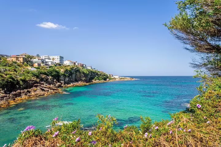 Turquoise waters of Bondi Beach coastline with rocky cliffs and residential buildings on the headland
