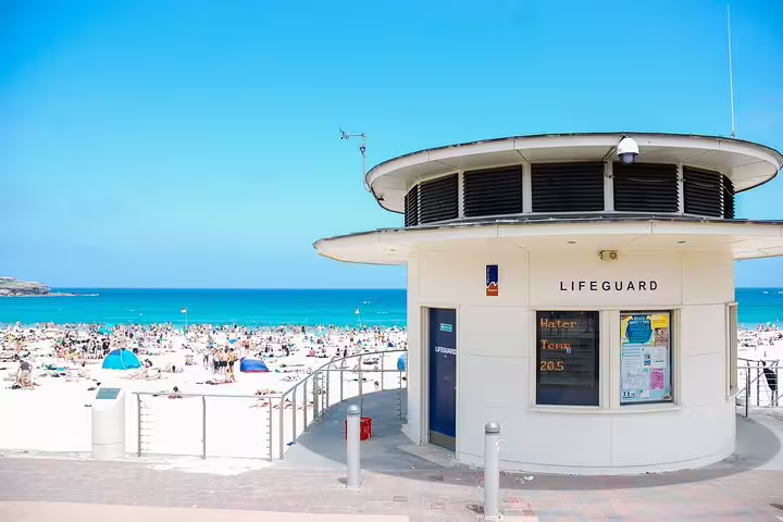 Bondi Beach lifeguard station with crowded sandy beach and turquoise ocean on a sunny day