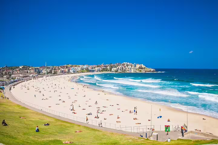 Aerial view of Bondi Beach with white sand, turquoise waves, sunbathers, and coastal buildings in Sydney