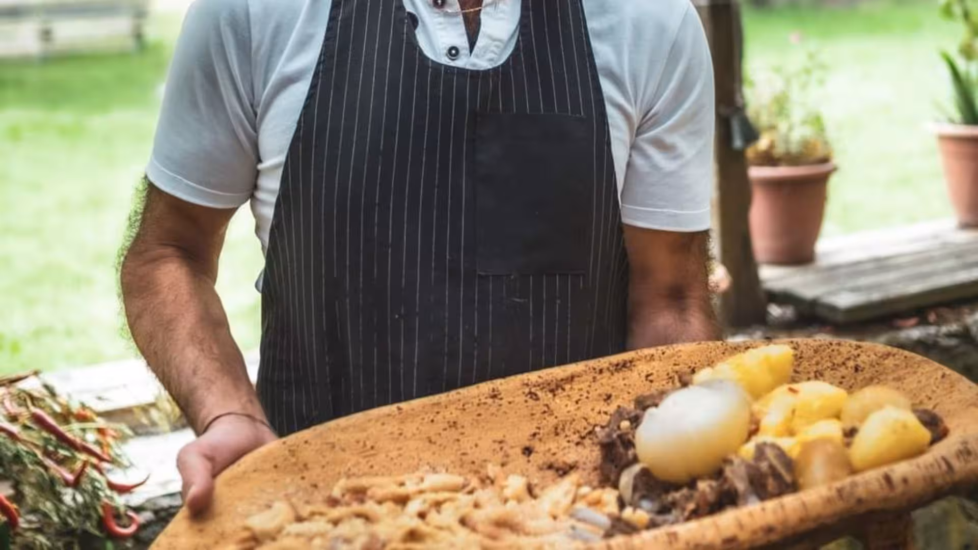 Man in apron presenting a traditional Sardinian lunch platter at a Bonorva farm.