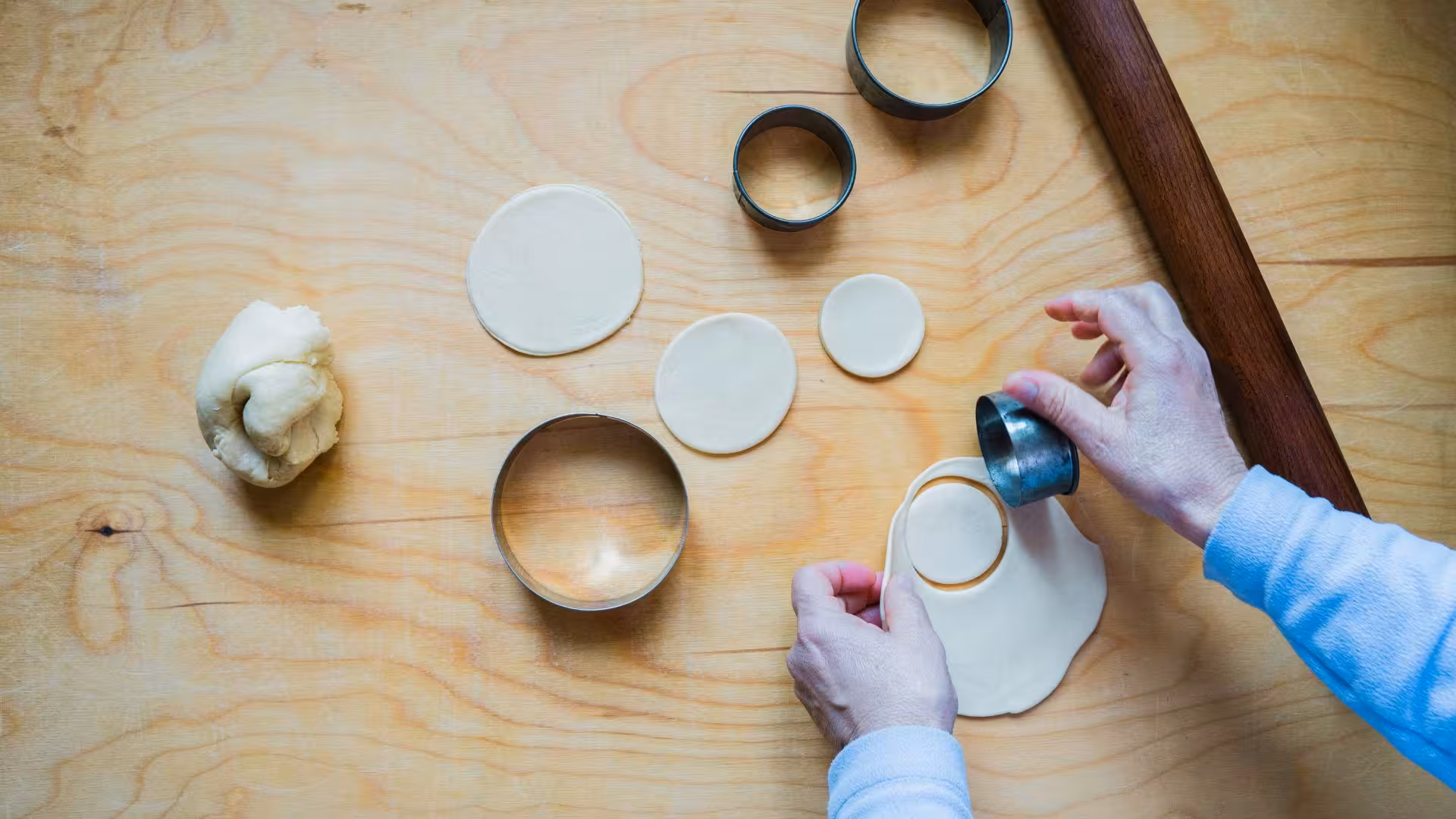 Hands cutting dough circles for seadas in authentic Sardinian cooking class in Bonorva.