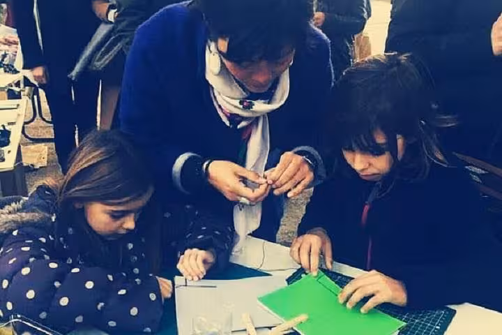 Participants learning stitching and folding during a bookbinding experience in Marseille Vieux Port workshop