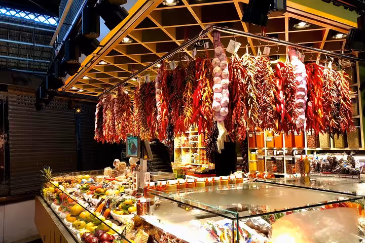 Colorful La Boqueria market stall with hanging chorizo, peppers and fresh fruit on a Barcelona food tour
