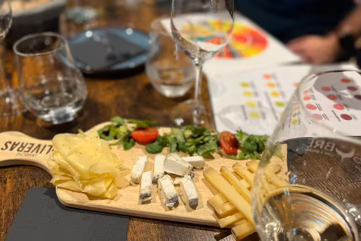 Cheese and charcuterie board with wine glasses during Bordeaux blind tasting of natural wines experience