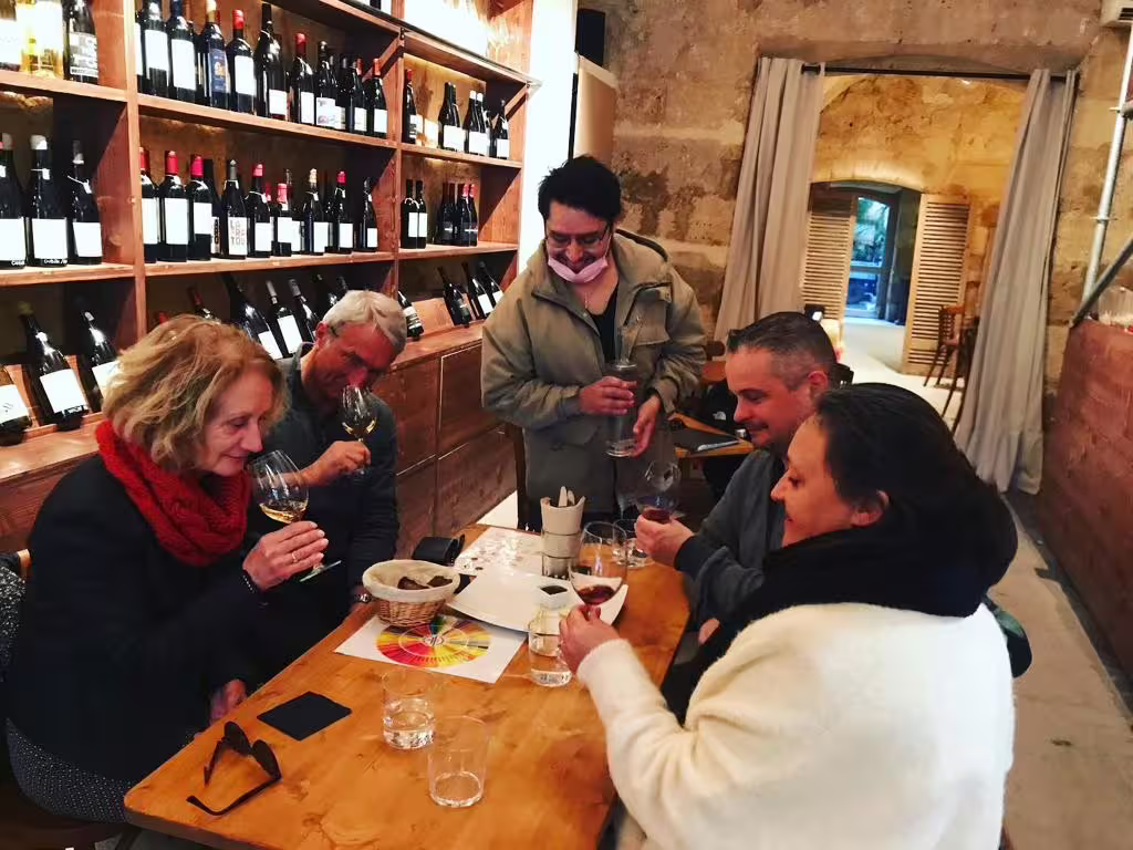 Guests swirl and sniff Bordeaux natural wine during blind tasting with cheese and charcuterie in wine shop