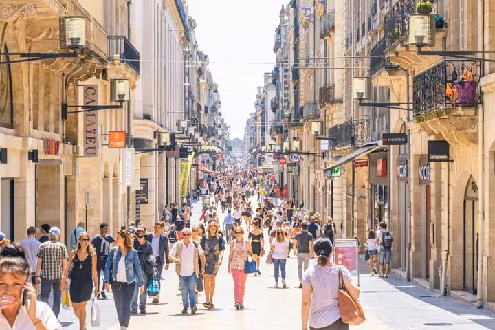 Crowds of tourists walking along a busy pedestrian shopping street in Bordeaux Old Town on a sunny day