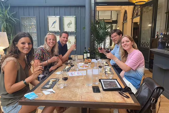 Small group Bordeaux wine history tour guests enjoying red wine and cheese tasting at a cozy bistro table