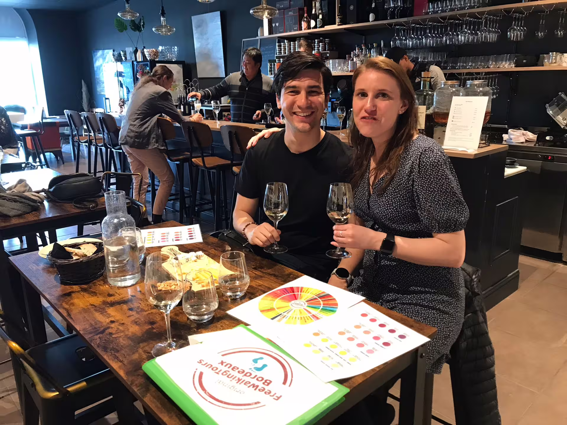 Guests tasting Bordeaux wines in a cozy wine bar, learning wine history with aroma wheel and tasting notes