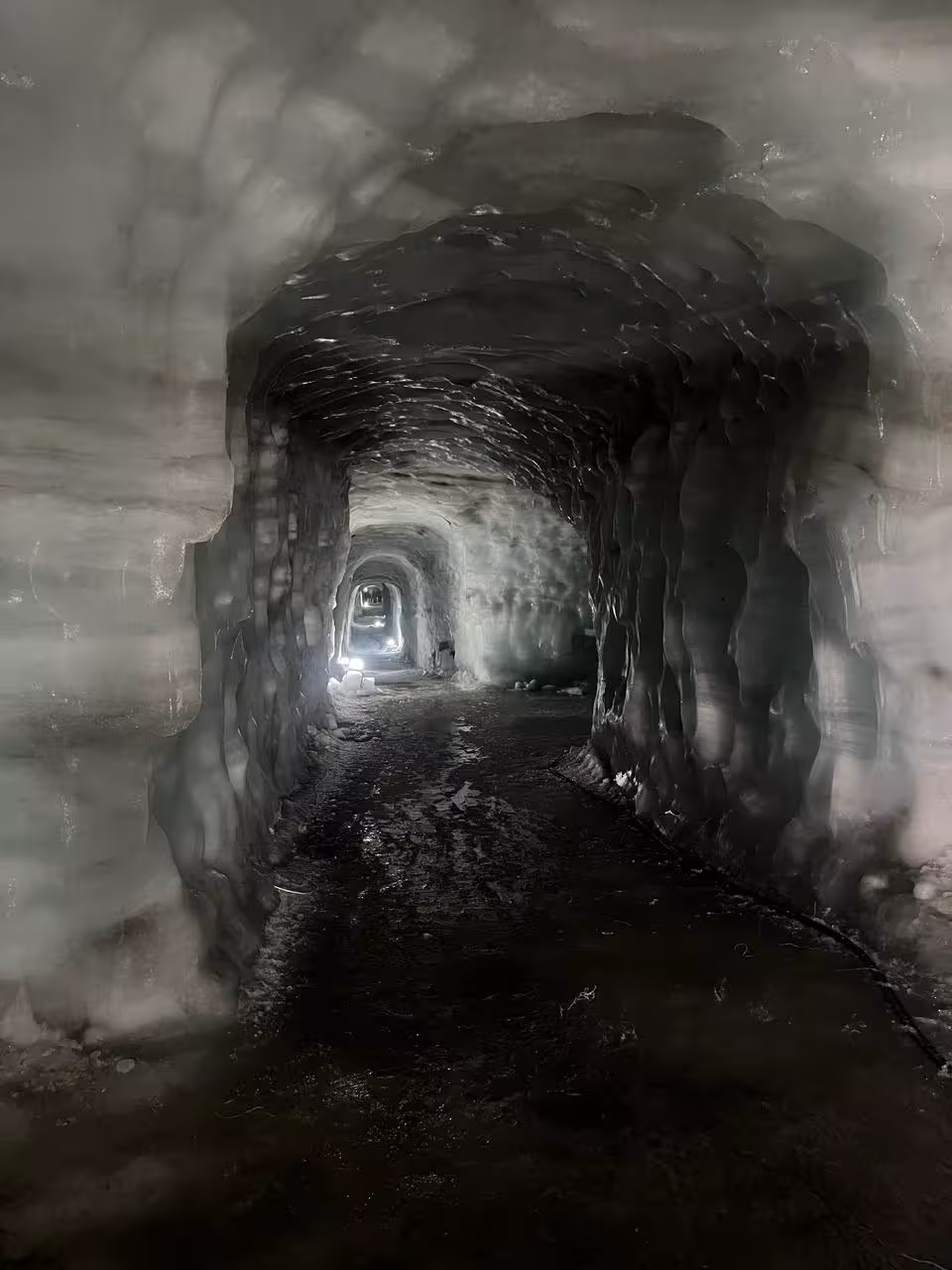 Ice tunnel cave corridor with glowing lights inside Borgarfjordur glacier, Iceland