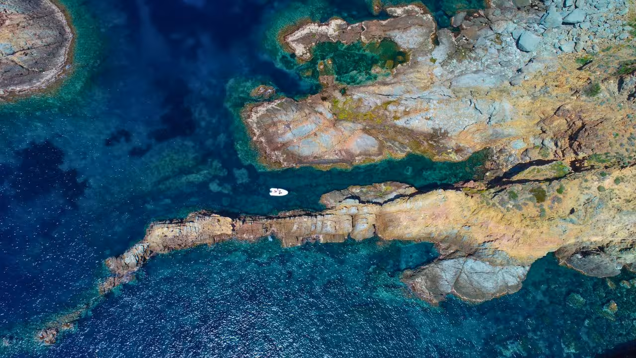 Aerial view of Capo Marrargiu's rocky coastline and vibrant blue waters, perfect for snorkeling adventures in Bosa.