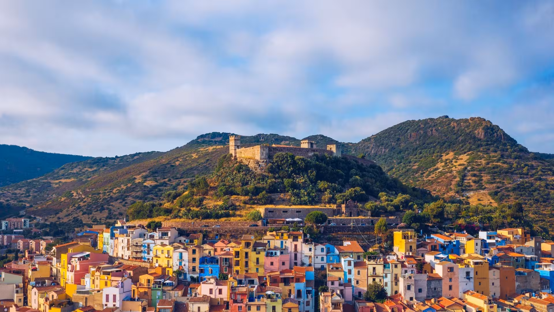 Stunning view of Bosa's colorful houses and historic castle, a highlight of the panoramic tour from Alghero.