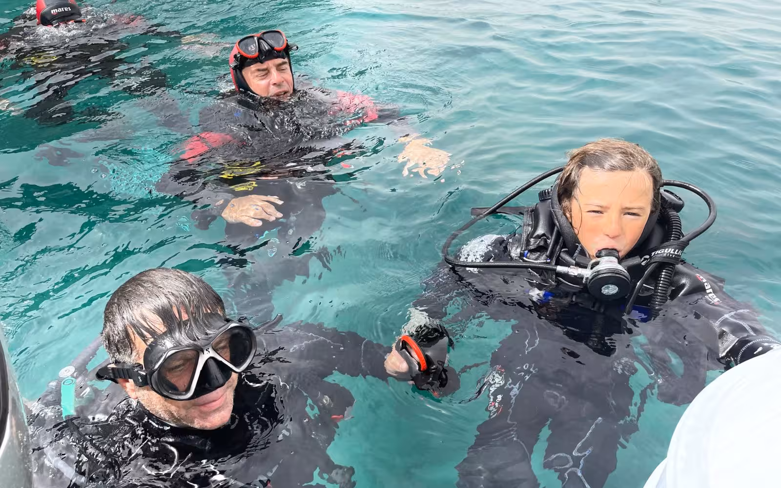 Group of divers in Bosa waters, experiencing the thrill of a diving baptism with full gear.