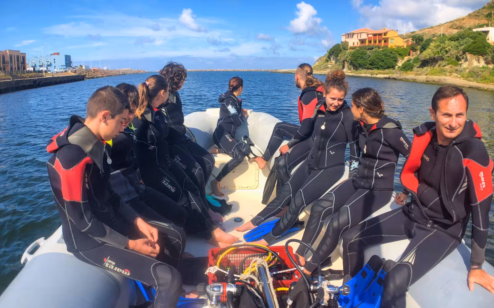 Diving group in wetsuits on a boat, preparing for Bosa's exciting diving baptism excursion.