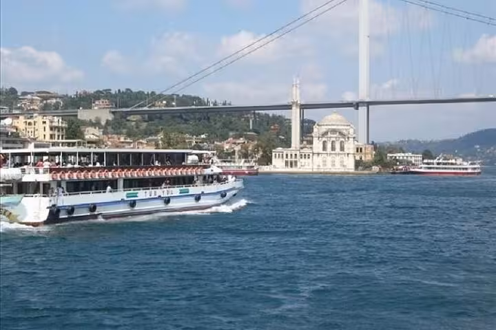 Bosphorus cruise boat passing Ortakoy Mosque and Bosphorus Bridge on Asia-Europe full-day Istanbul tour