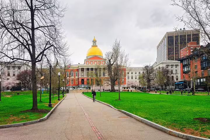 Massachusetts State House golden dome viewed from Boston Common walking path on overcast day
