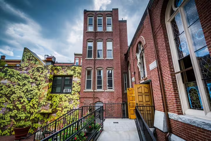 Historic red brick buildings in Boston's North End neighborhood with ivy-covered wall and church facade