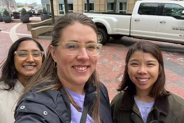 Three smiling women taking a selfie on a brick plaza in Boston's North End neighborhood