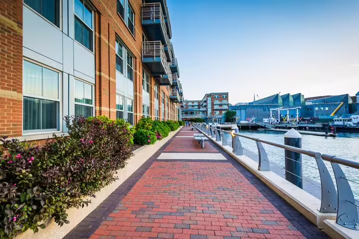 Brick waterfront promenade along Boston harbor with modern residential buildings and marina views