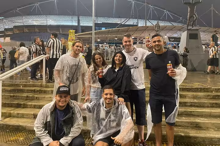 Tour group in rain ponchos outside Nilton Santos Stadium joining locals for a Botafogo soccer match in Rio