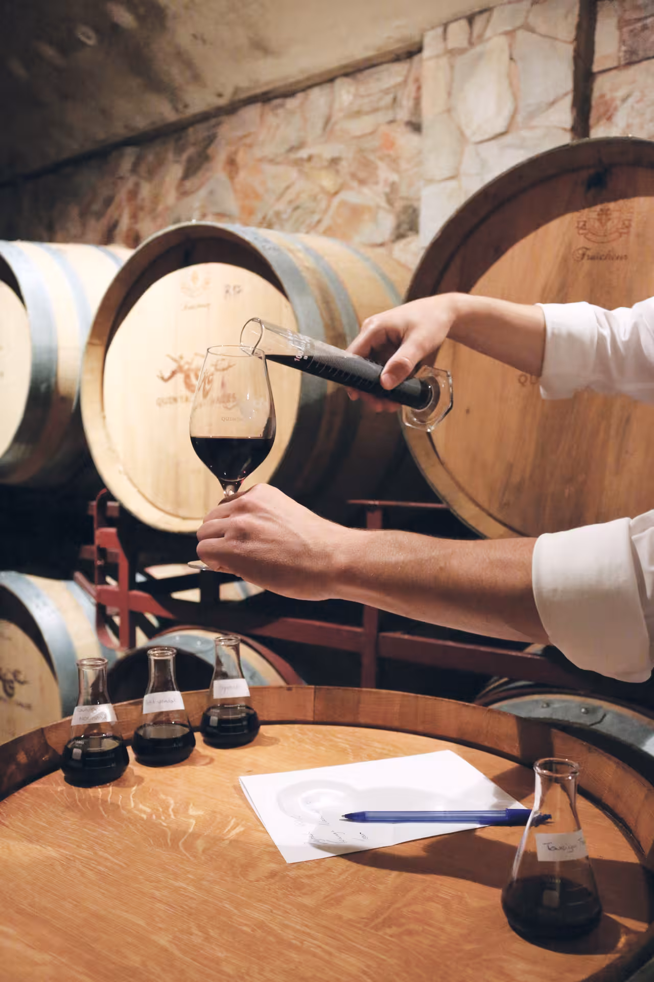Winemaker pouring red wine into a glass from oak barrels during an interactive bottle blending workshop at Quinta dos Vales wine estate Portugal