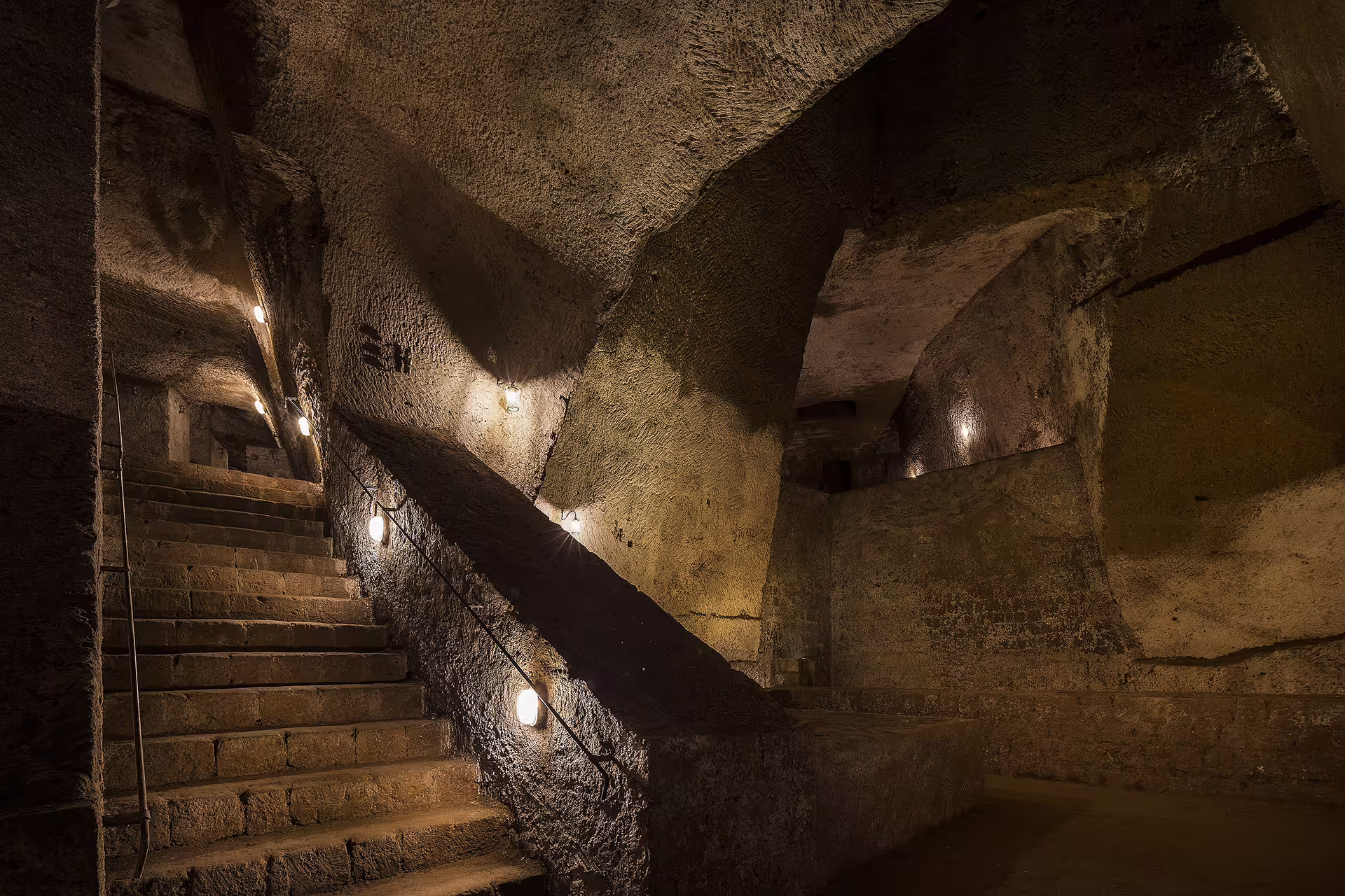 Stone stairways and rugged tuff walls of the Bourbon Tunnel showcase Naples’ dramatic underground history by night
