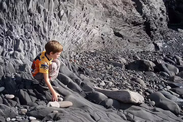 Young boy exploring volcanic rock formations on Snaefellsnes Peninsula coastline in Iceland