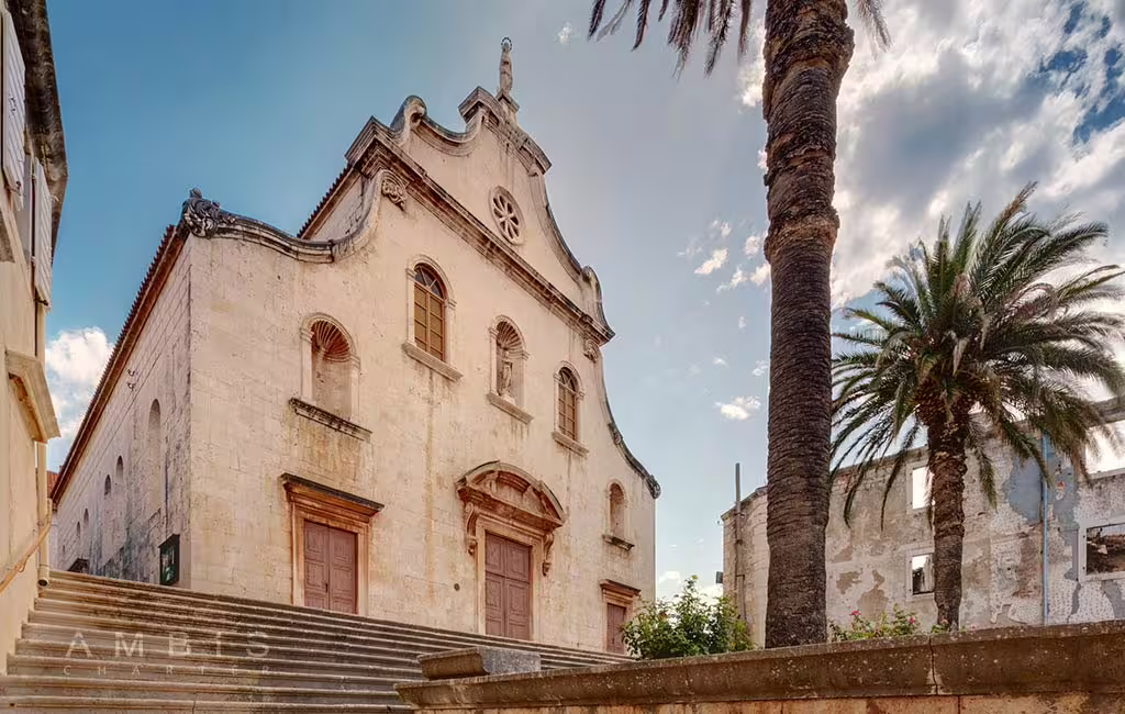 Historic stone church and palm trees in Brac town, cultural sightseeing on Brac and Solta private boat tour
