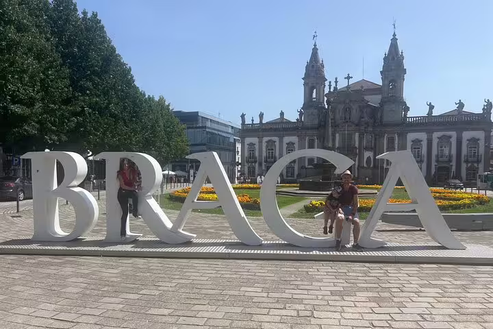 Travelers by the BRAGA sign at Avenida Central, a key stop on the Braga self-guided scavenger hunt tour