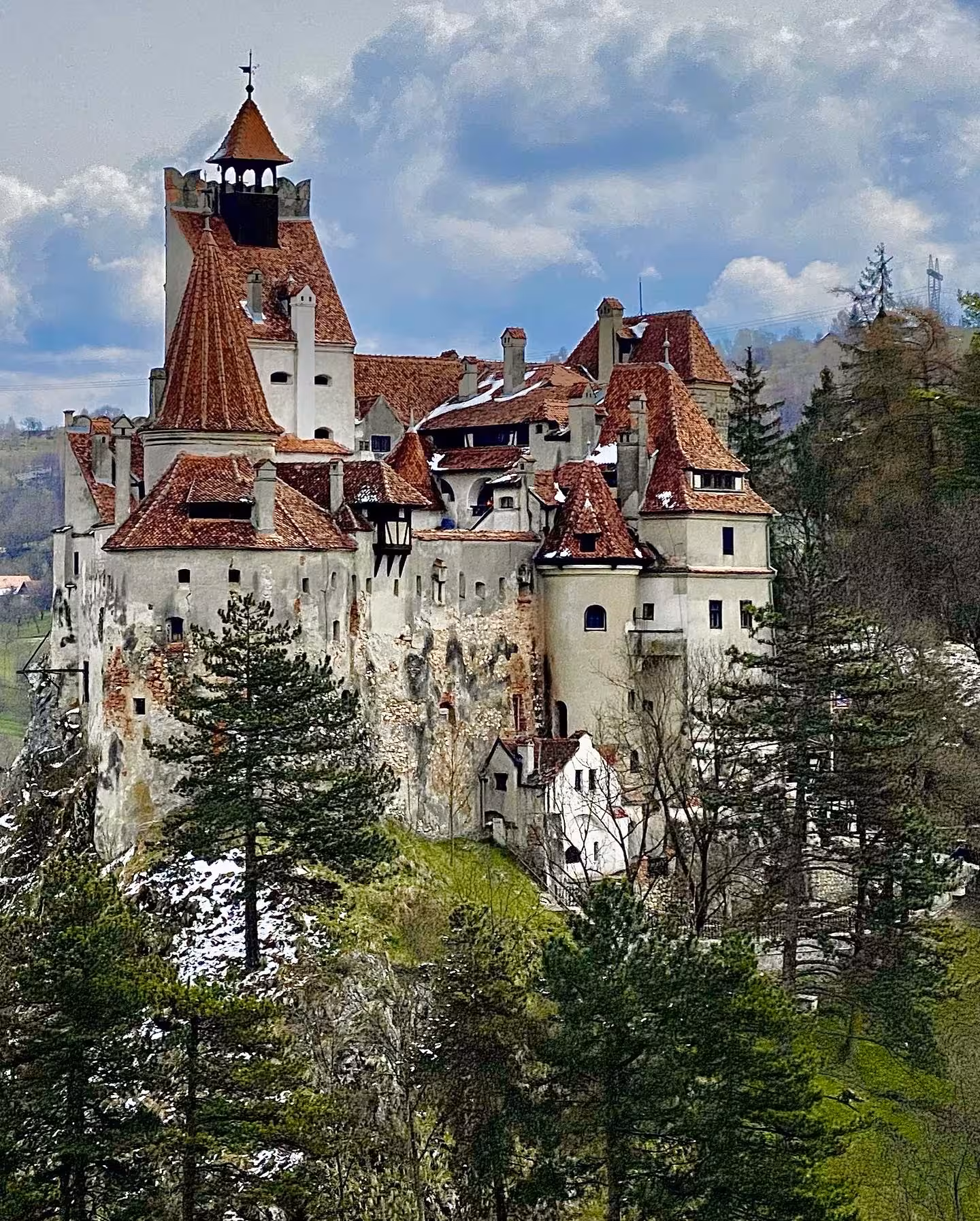 Bran Castle perched on rocky cliff surrounded by pine trees, Transylvania, Romania