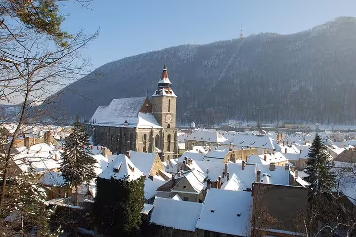 Snow-covered medieval town of Brașov with Black Church tower and Carpathian mountains in winter, Transylvania Romania