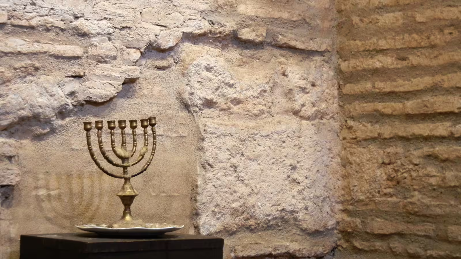 Brass menorah displayed against ancient stone wall in Cordoba, seen on a private Costa del Sol to Cordoba tour