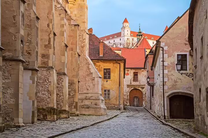 Cobblestone lane in Bratislava Old Town with Bratislava Castle rooftops on a self-guided scavenger hunt tour