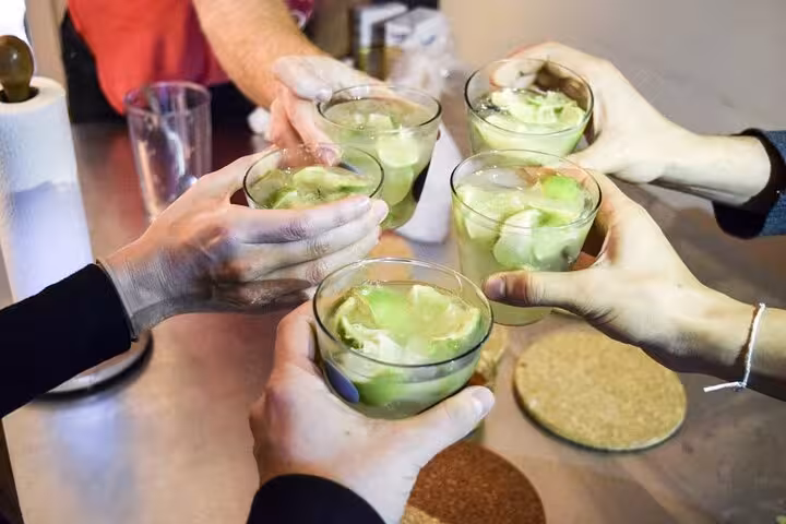 Friends clinking glasses of Caipirinhas, enjoying a vibrant cocktail-making experience in Rio de Janeiro.