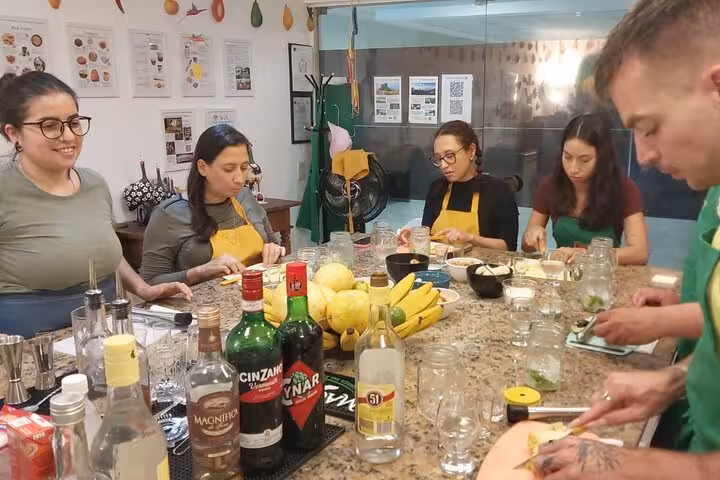 Group of people prepare ingredients for Brazilian cocktails, surrounded by fresh fruits and spirits at Ipanema Beach class.