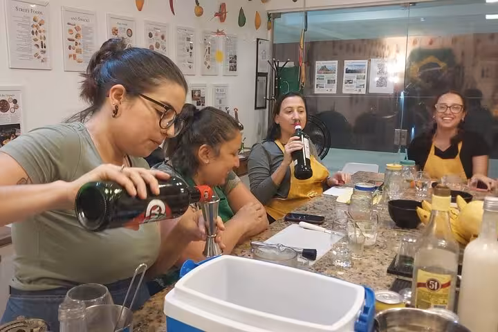 Participants enjoying a lively Brazilian cocktail-making session, pouring drinks and sharing laughs in a festive setting.