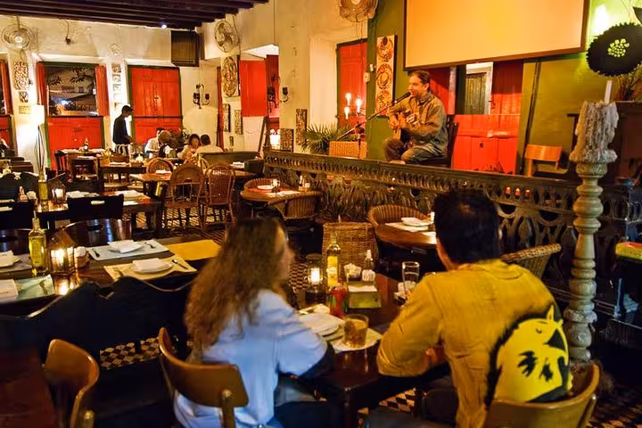 Cozy Brazilian diner with live music, candlelit tables, and patrons enjoying a caipirinha in a vibrant atmosphere.
