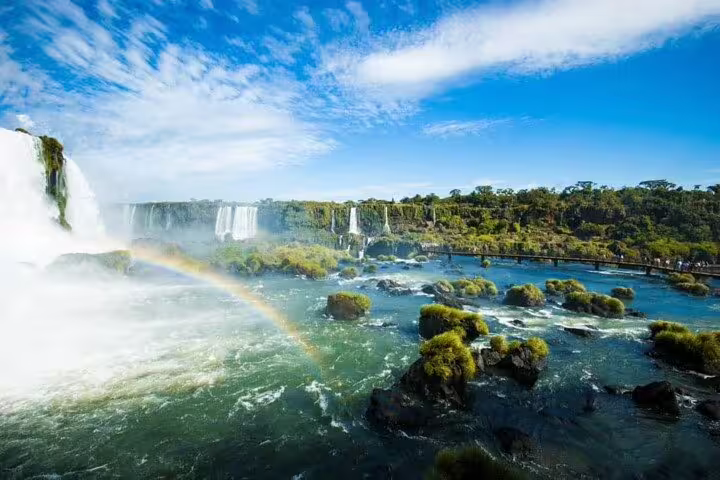 Stunning view of Brazilian Falls with a vibrant rainbow arching over the cascading water and lush landscape.