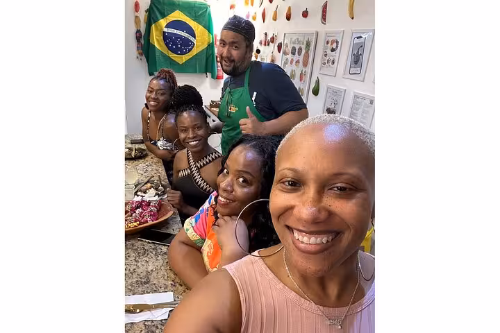 Group enjoying Brazilian food with a chef in a vibrant kitchen, showcasing local cuisine and culture.