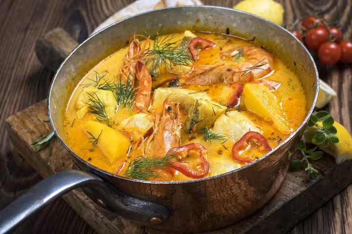 Steaming pot of Brazilian moqueca with shrimp, fish, and peppers, highlighting Rio's culinary delights.