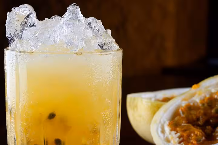 Refreshing Brazilian passion fruit caipirinha cocktail with ice, showcasing vibrant tropical flavors.