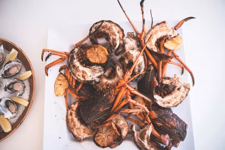 Grilled seafood platter with crab and lemon, served alongside oysters with lemon wedges, in a Rio culinary class.