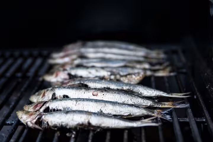 Fresh sardines sizzling on a grill during a Rio seafood cooking class, highlighting traditional Brazilian flavors.