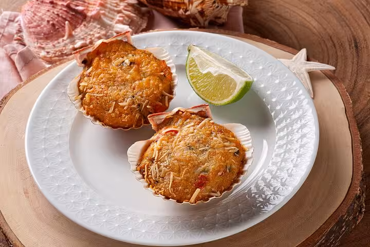 Delicious baked Brazilian seafood shells garnished with lime on a decorative plate, showcasing authentic flavors.