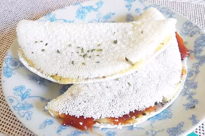 Two Brazilian tapioca crepes filled with vibrant red filling, served on a decorative plate for a culinary tour.