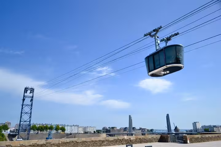 Cable car gondola suspended over Brest city skyline on a clear blue sky day