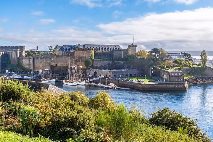 Historic Brest castle and harbor with tall ships docked along the medieval stone fortress walls