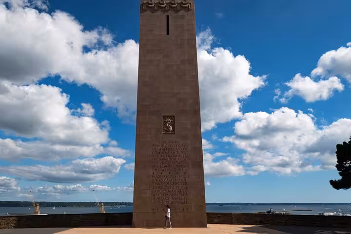 Tall stone memorial tower monument in Brest with inscriptions, overlooking the harbor under blue sky