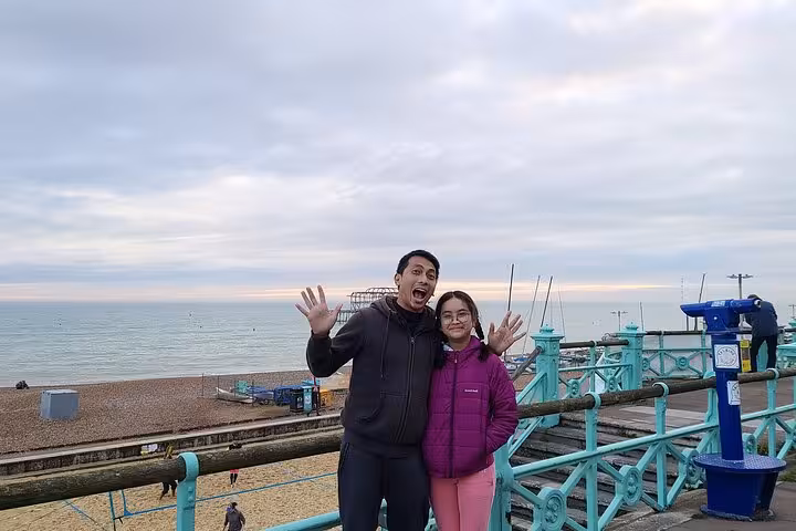 Couple posing happily on Brighton pier with beach and sea in background