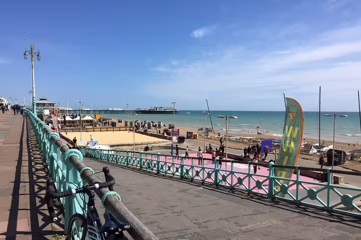 Brighton seafront promenade with pier, beach, and turquoise railings on a sunny day