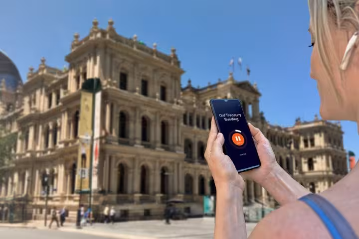 Woman holding smartphone with audio tour app at Old Treasury Building, Brisbane